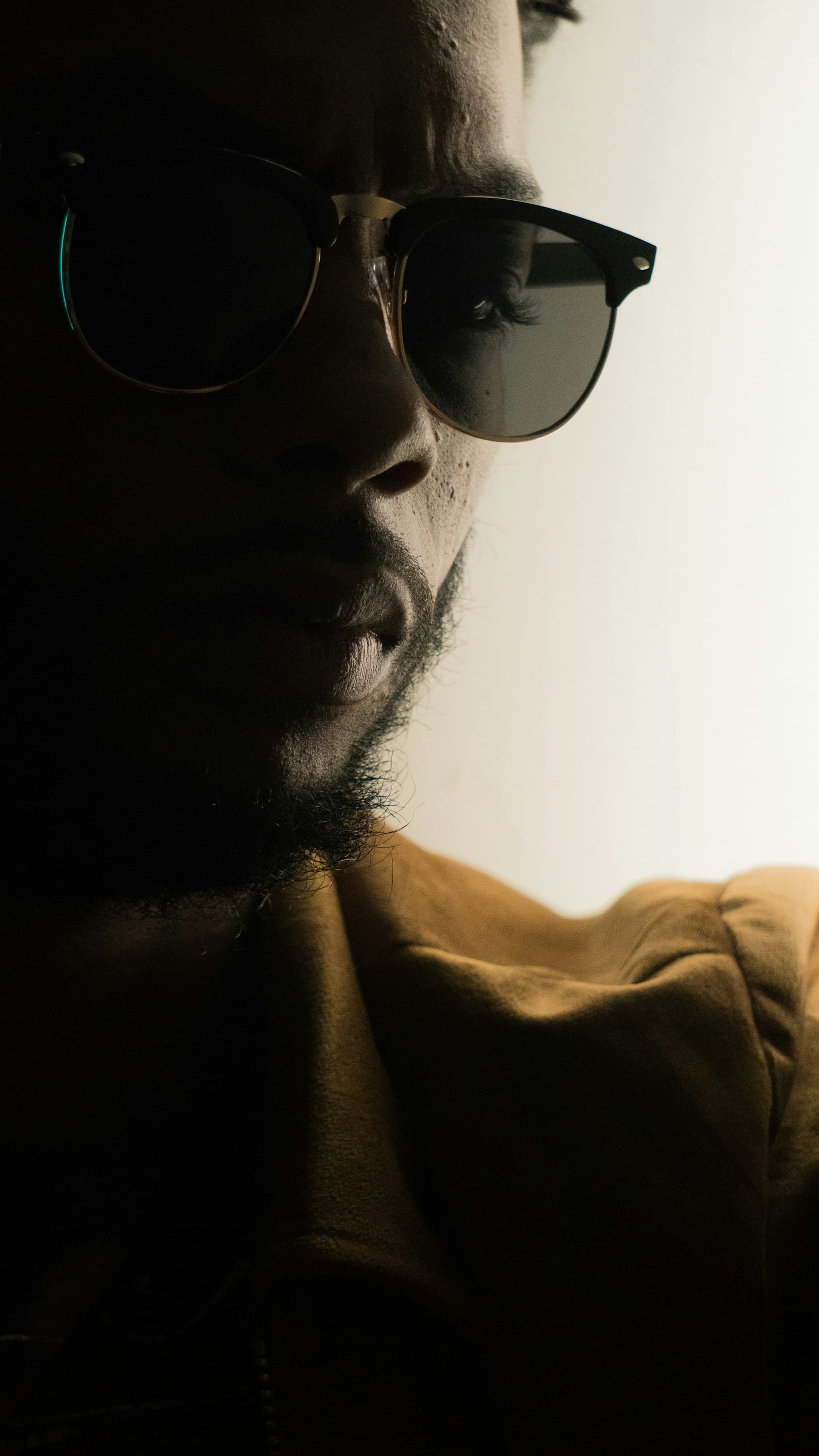 Close portrait in deep shadow wearing browline sunglasses